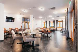 - une salle à manger avec des tables, des chaises et des fenêtres dans l'établissement Villa Bellini Borszék, à Borsec