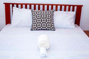 Cama blanca con cabecero rojo y almohadas blancas en EAZY BREEZY BACKPACKERS en Dar es Salaam