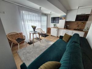 ein Wohnzimmer mit einem grünen Sofa und einer Küche in der Unterkunft Zatoka Apartamenty in Władysławowo