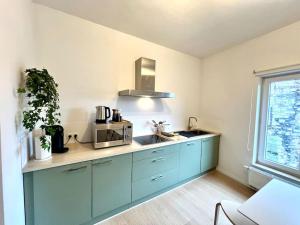 a kitchen with blue cabinets and a microwave at Duplex chic et spacieux - Hypercentre in Liège