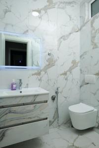 a white bathroom with a sink and a toilet at Travelers' Korça Home in Korçë +21 photos