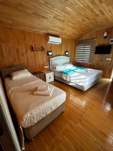 two beds in a room with wooden walls and wood floors at Garden Pansiyon Çıralı in Kemer