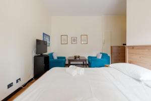 a bedroom with a white bed and blue chairs at Forlanini - Functional Studio with Balcony! in Milan