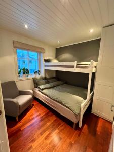 sypialnia z 2 łóżkami piętrowymi i krzesłem w obiekcie Flaskebekk at Nesodden with unbeatable Oslo Fjord views and a private beach hut w mieście Nesoddtangen