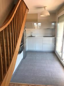 a kitchen with white cabinets and a wooden staircase at Appartement à côté de la plage avec piscine climatisé in Hendaye