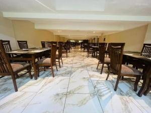 a dining room with tables and chairs on a marble floor at Pearl Inn Hotel in Karachi