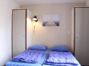 a bedroom with two beds with blue pillows at Tidy bungalow with garden located in natural area in Vledder