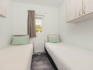 two twin beds in a room with a window at Cozy chalet with garden at the edge of the forest in Rijssen