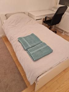 a bed with two green towels on top of it at Bright and cozy room next to the airport in Kampenhout