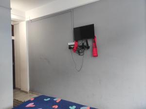 una habitación con una pared blanca y TV. en Hotel Norbuling en Dirāng