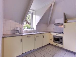 d'une cuisine avec des placards blancs, un évier et une fenêtre. dans l'établissement Cozy holiday home with a garden near Zwolle, à Dalfsen