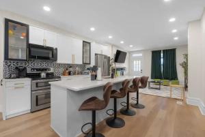 a kitchen with white cabinets and a kitchen island with bar stools at 5 Bedrooms Sleeps 14 Hot Tub Fire Pit in Columbus