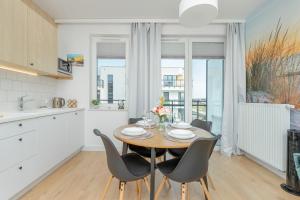 Una cocina y un comedor con mesa y sillas. en Nowy Świat Stylish, Seaside Apartment with Balcony & Parking Puck by Noclegi Renters, en Puck