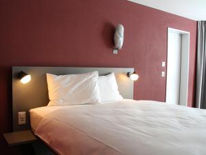 a bedroom with a white bed with a red wall at Stockberg hotel & apartments in Siebnen