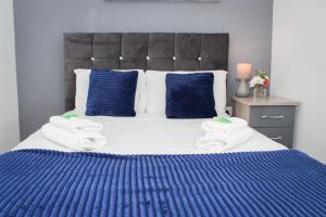 a bed with blue and white sheets and blue pillows at Serviced Apartment In Liverpool City Centre - Free Parking - Balcony - by Happy Days in Liverpool