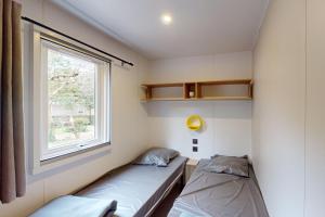 two beds in a small room with a window at CAMPING SAINT GABRIEL *** in Tarascon