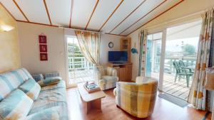 - un salon avec un canapé et une télévision dans l'établissement Mobil Home 40 avec piscines, à Brem-sur-Mer