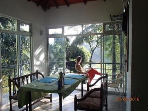 a child sitting at a table in a room with windows at Kandy River Breeze in Kandy