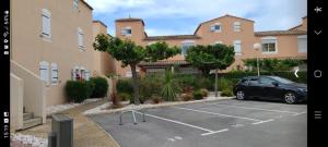 une voiture garée dans un parking en face d'un bâtiment dans l'établissement Appartement au calme à l'Orée du golf 1, au Cap d'Agde