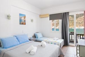 a bedroom with two beds and a balcony at Simeon Rooms & Apartments in Kamares