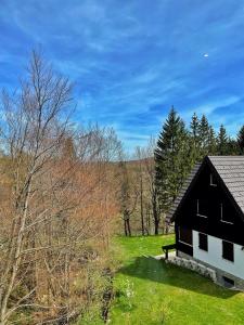 a black and white house in a field with trees at Guest house Ivica i Marica in heart of the national park Plitvička jezera in Plitvica selo
