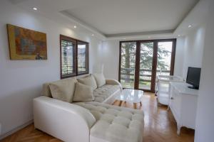 a living room with a white couch and a television at Villa Xenia Kosmaj in Koraćica