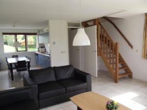 ein Wohnzimmer mit einem schwarzen Sofa und einem Tisch in der Unterkunft Semi detached house in Franeker with a shared pool in Franeker