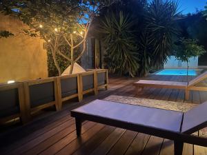 una terraza de madera con un banco y una piscina en Villa dans son écrin de verdure, en La Ciotat