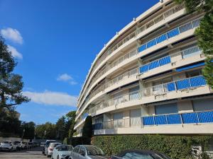 a building with cars parked in a parking lot at Cap d'Antibes Port Aubernon 3P vue Mer Piscine in Antibes