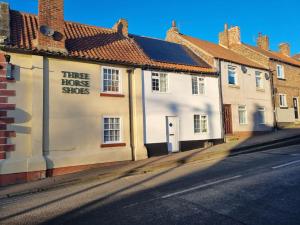 a building with a sign that reads three house shops at Blacksmiths Cottage in Brompton