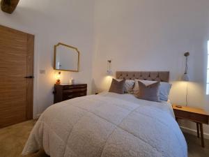 a bedroom with a large bed with a dresser and a mirror at Blacksmiths Cottage in Brompton