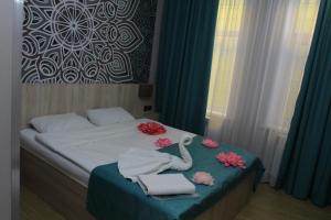 Un dormitorio con una cama con toallas y flores. en Altyn Shatyr Hotel and Restaurant en Aksay