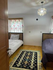 a bedroom with two beds and a rug on the floor at Florija’s Guesthouse in Dardhë