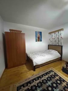 a bedroom with a bed and a cabinet and a rug at Florija’s Guesthouse in Dardhë