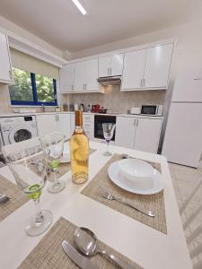- une cuisine blanche avec une table, des verres et une bouteille de vin dans l'établissement Marina Gardens, delightful 2 bedroom apartment, à Paphos