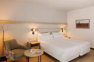 Sercotel Amistad Murcia في مورسية: غرفه فندقيه سرير ابيض وكرسي