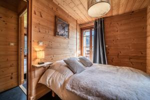 Charmant Chalet Aurore في مورزين: غرفة نوم بسرير في غرفة خشبية