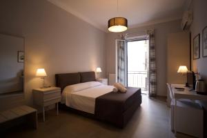 Un dormitorio con una cama y un escritorio y una ventana. en Donna Franca Rooms and Suite, en Palermo