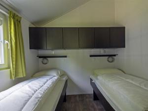 two beds in a room with green curtains at Cozy lodge with a dishwasher at a holiday park in the Achterhoek in Brinkheurne