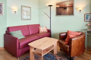 ein Wohnzimmer mit einem lila Sofa und einem Stuhl in der Unterkunft Fördeblick 7 in Laboe