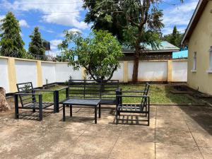 een groep banken en een tafel en stoelen bij COZY NYUMBA in Arusha