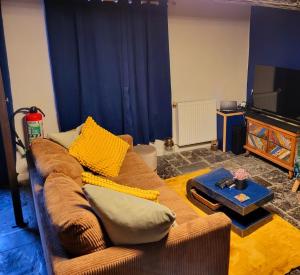 a living room with a brown couch and a television at L'Arsouille Gîte Rural Doische in Doische
