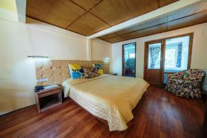 a bedroom with a large bed and a chair at Hotel Shambhala Resort in Leh