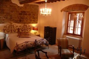 a bedroom with a bed and a chair and a chandelier at La Piazzetta Toscana B&B in Campiglia Marittima