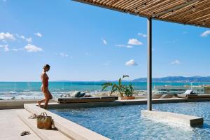 a woman walking by a swimming pool at a resort at Iberostar Selection Llaut Palma- Adults Only in Playa de Palma