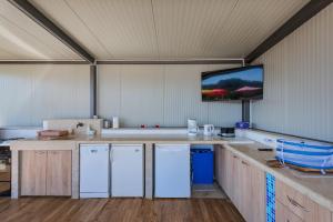 une cuisine avec des appareils électroménagers blancs et une télévision au mur dans l'établissement Family home with hydromassage pool & fun activities, à Žminj