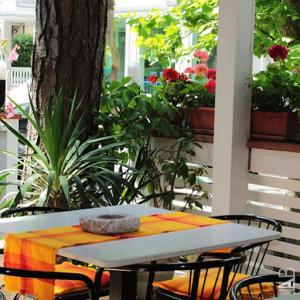 uma mesa e cadeiras num alpendre com flores em hotel Plaza em Cesenatico