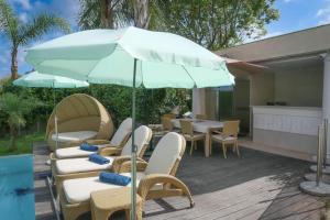 um pátio com cadeiras, um guarda-sol e uma mesa em Stunning private Villa with Pool in Antibes em Antibes