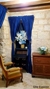 Habitación con silla y ventana con cortinas azules. en Évasion ACCES PMR en Les Roches-lʼÉvêque