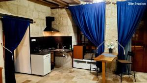 a kitchen with blue curtains and a table and a sink at Évasion in Les Roches-lʼÉvêque +5 photos